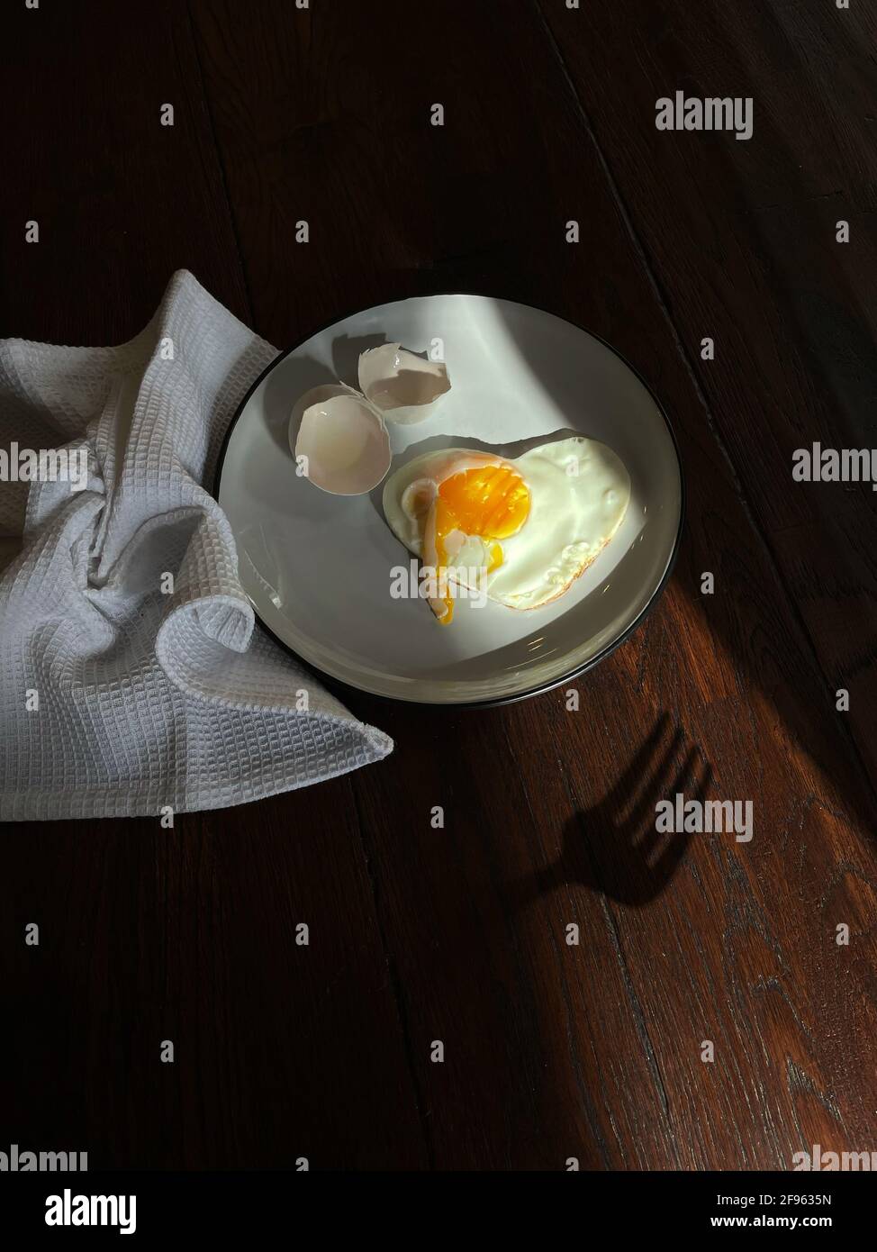 Œuf frit sous forme de coeur sur un plaque blanche avec une coque Banque D'Images