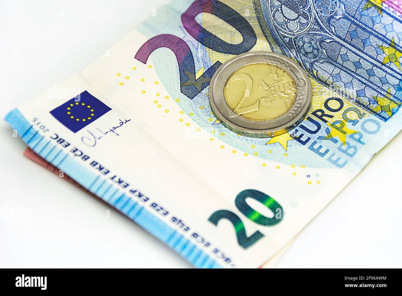 Une pièce de 2 euros usagée se tenant au-dessus d'un billet de 20 euros.  Économie et finance dans l'Union européenne Photo Stock