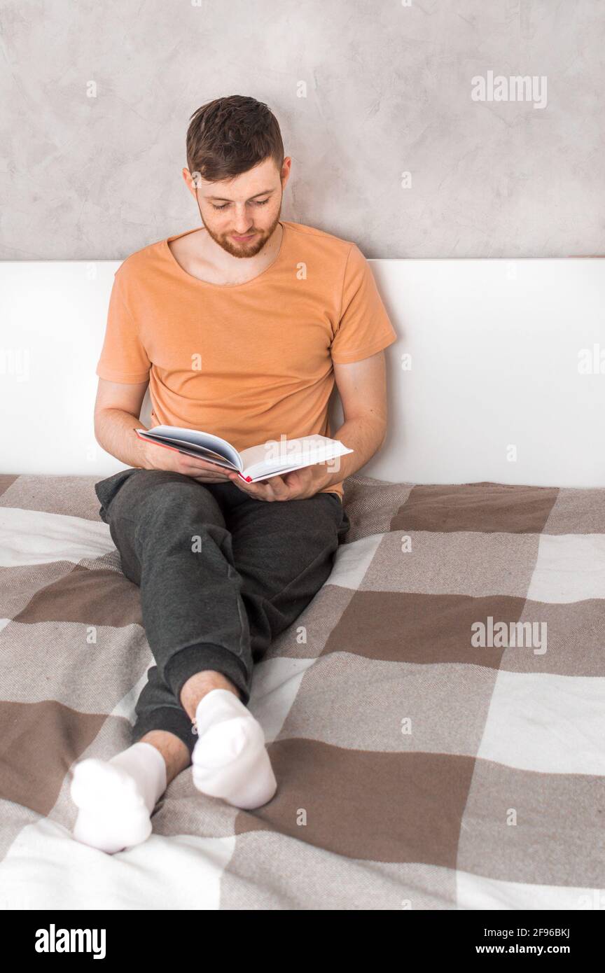 un jeune homme lit un livre au lit. Portrait. Photo verticale Banque D'Images