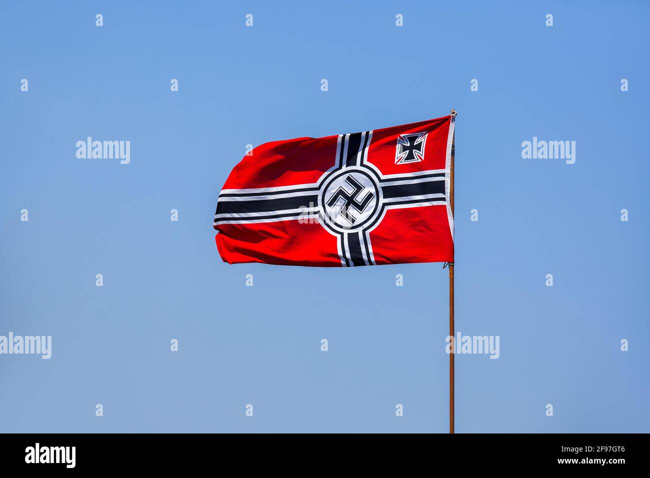 Drapeau nazi allemand agitant dans le vent contre un fond bleu ciel, un symbole historique sur un mât avec des symboles. Banque D'Images
