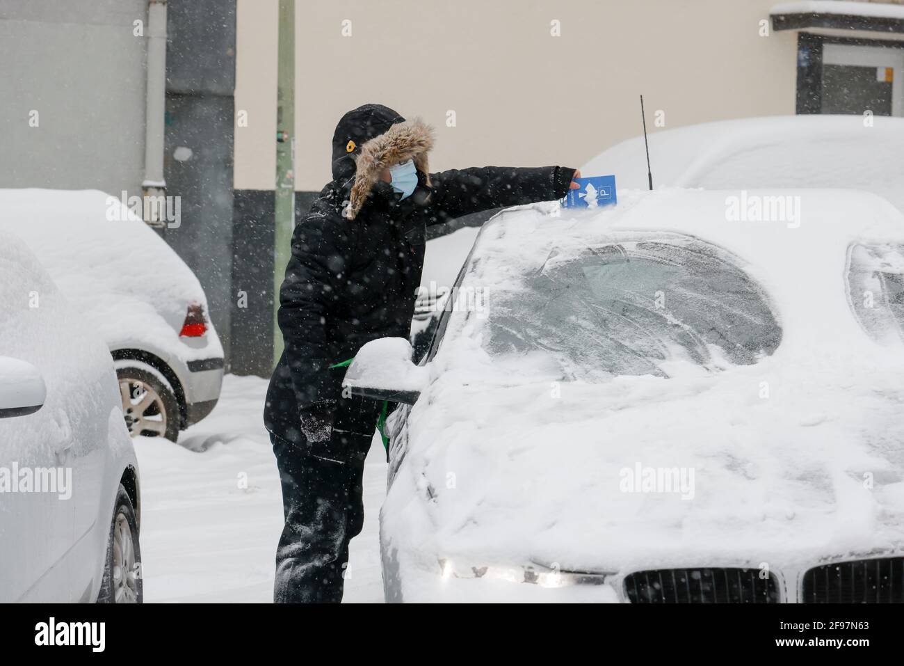 Essen, Rhénanie-du-Nord-Westphalie, Allemagne - début de l'hiver dans la région de la Ruhr, conducteur avec masque égratignures neige et glace de la voiture avec disque de stationnement en temps de la corona pandémie. Banque D'Images