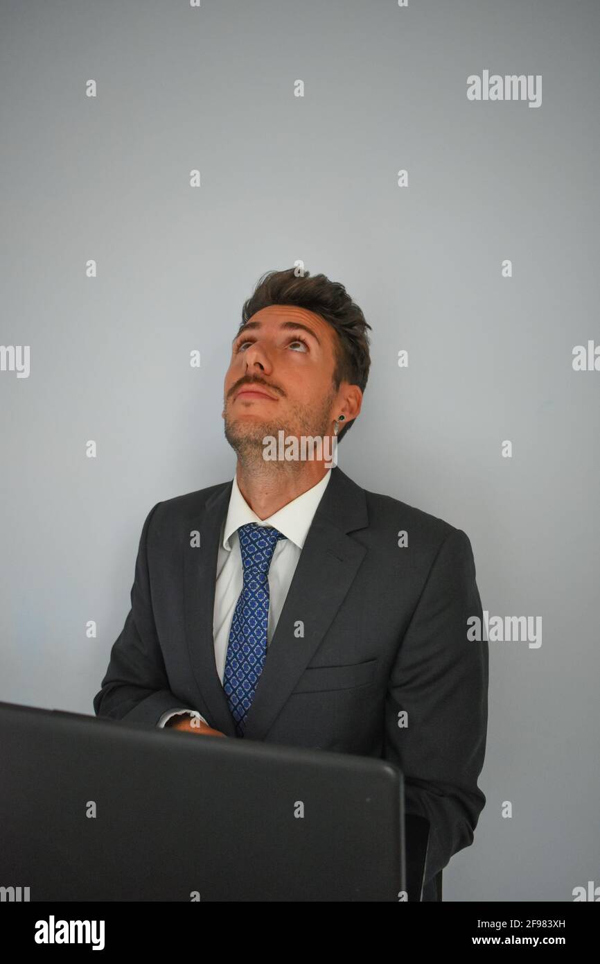 Homme d'affaires espagnol dans un costume regardant vers le haut en face d'un ordinateur portable Banque D'Images