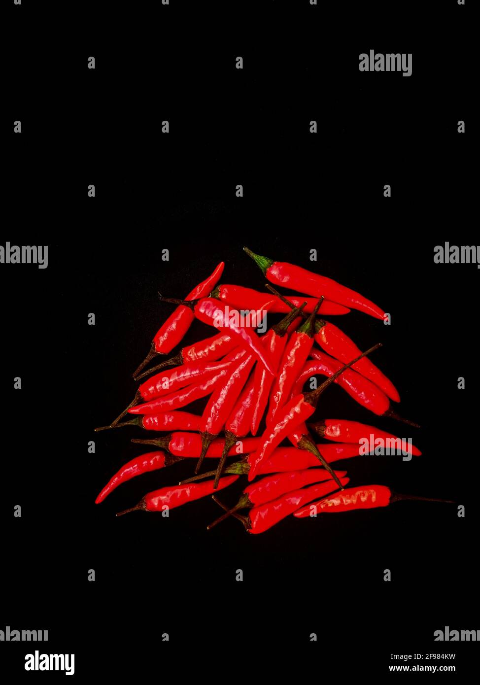 Tas de piments rouges chauds sur fond noir, vue du dessus Banque D'Images