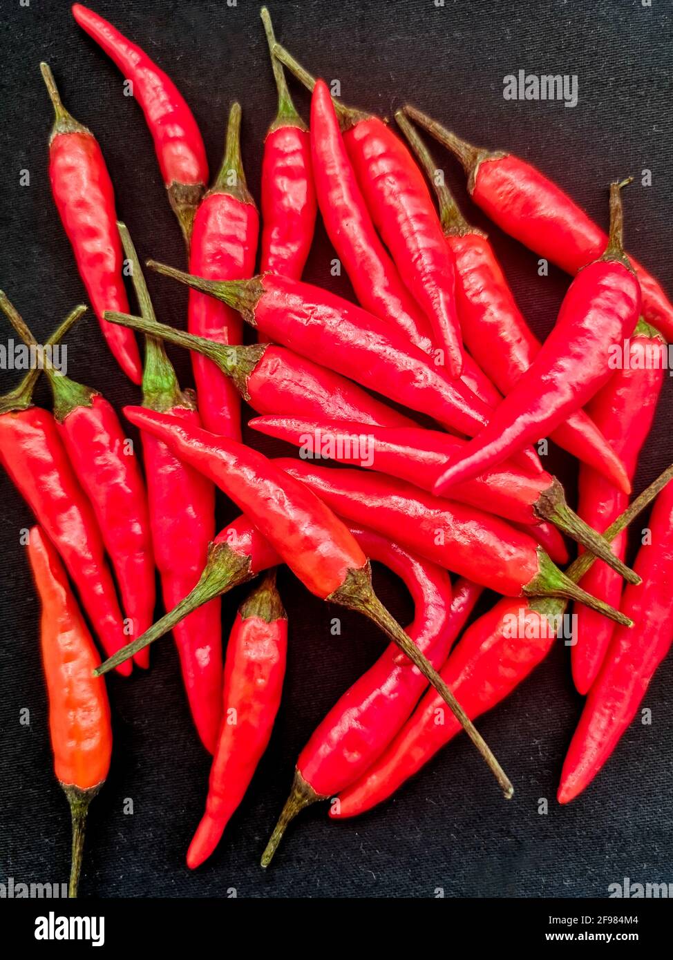 Tas de piments rouges chauds sur fond noir, vue du dessus Banque D'Images