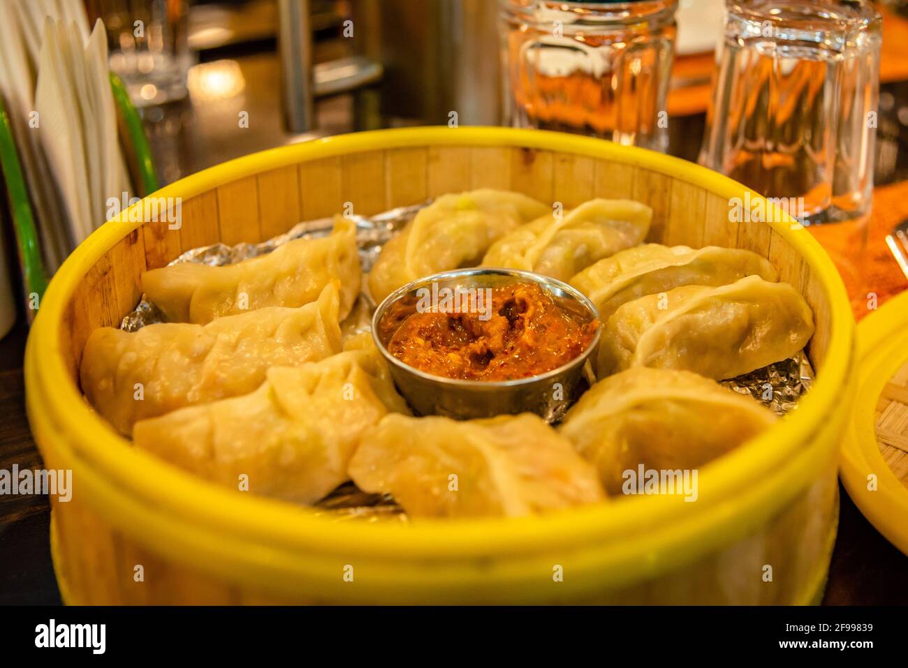 Mise au point sélective de Momos traditionnels à la vapeur tibétienne dans un cuiseur vapeur en bambou servi avec chutney de tomates ou trempette. Banque D'Images