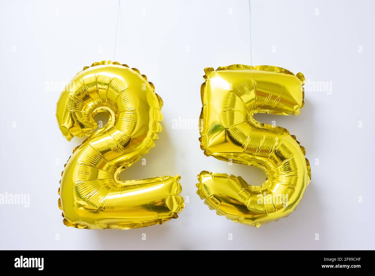 25 ans - image symbolique d'un anniversaire ou d'une célébration - deux ballons d'or avec les numéros deux et cinq pendent dans un bureau. Banque D'Images