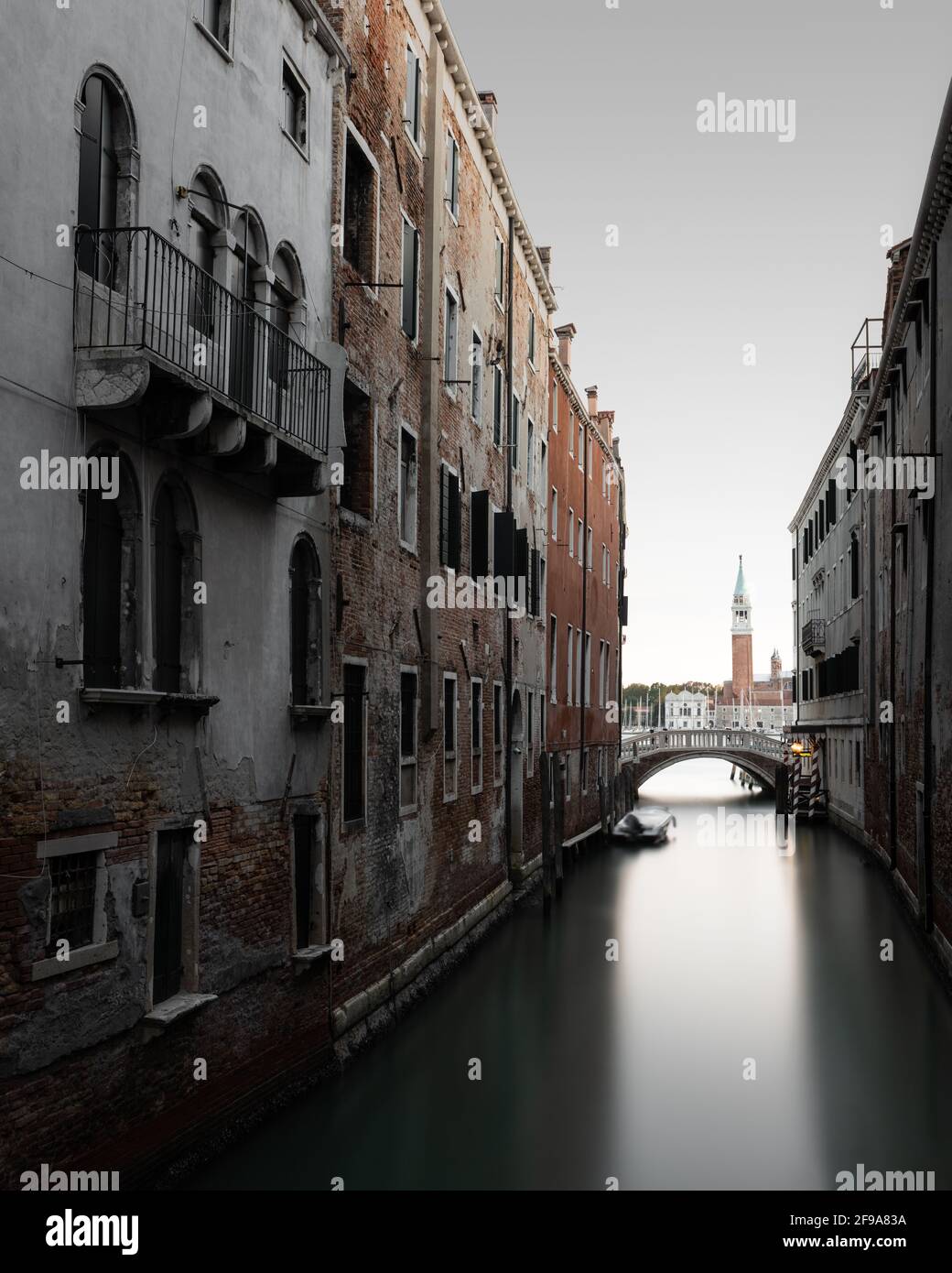 Canal typique entre les anciens bâtiments de Venise. En arrière-plan, vous pouvez voir le campanile de la petite île de San Giorgio Maggiore. Banque D'Images