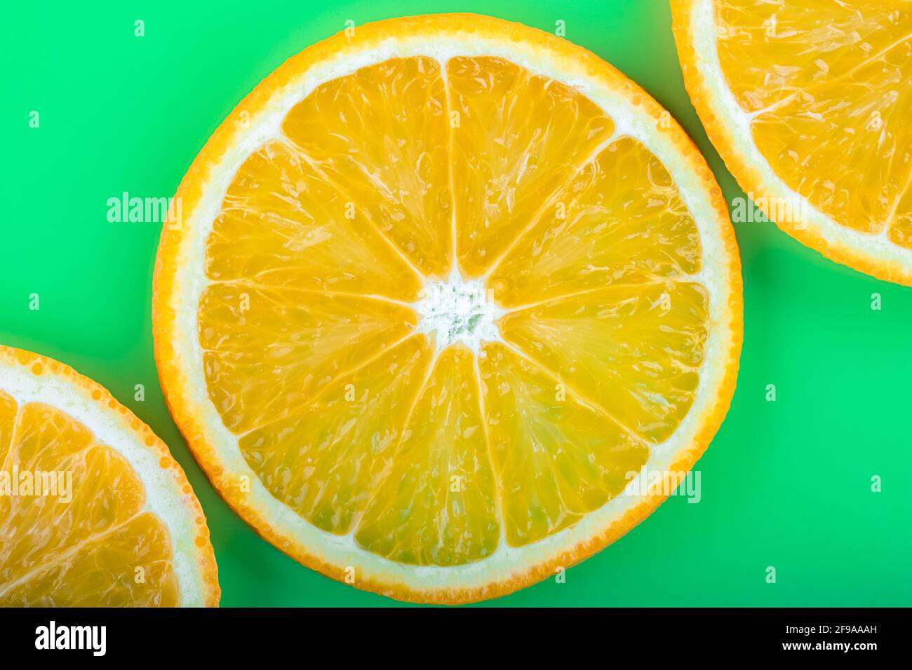 Motif d'été tropical lumineux avec gros plan de fruits orange sur fond vert. Tranches d'agrumes juteux, concept de vitamine C, papier peint abstrait amusant, interdiction de l'art Banque D'Images