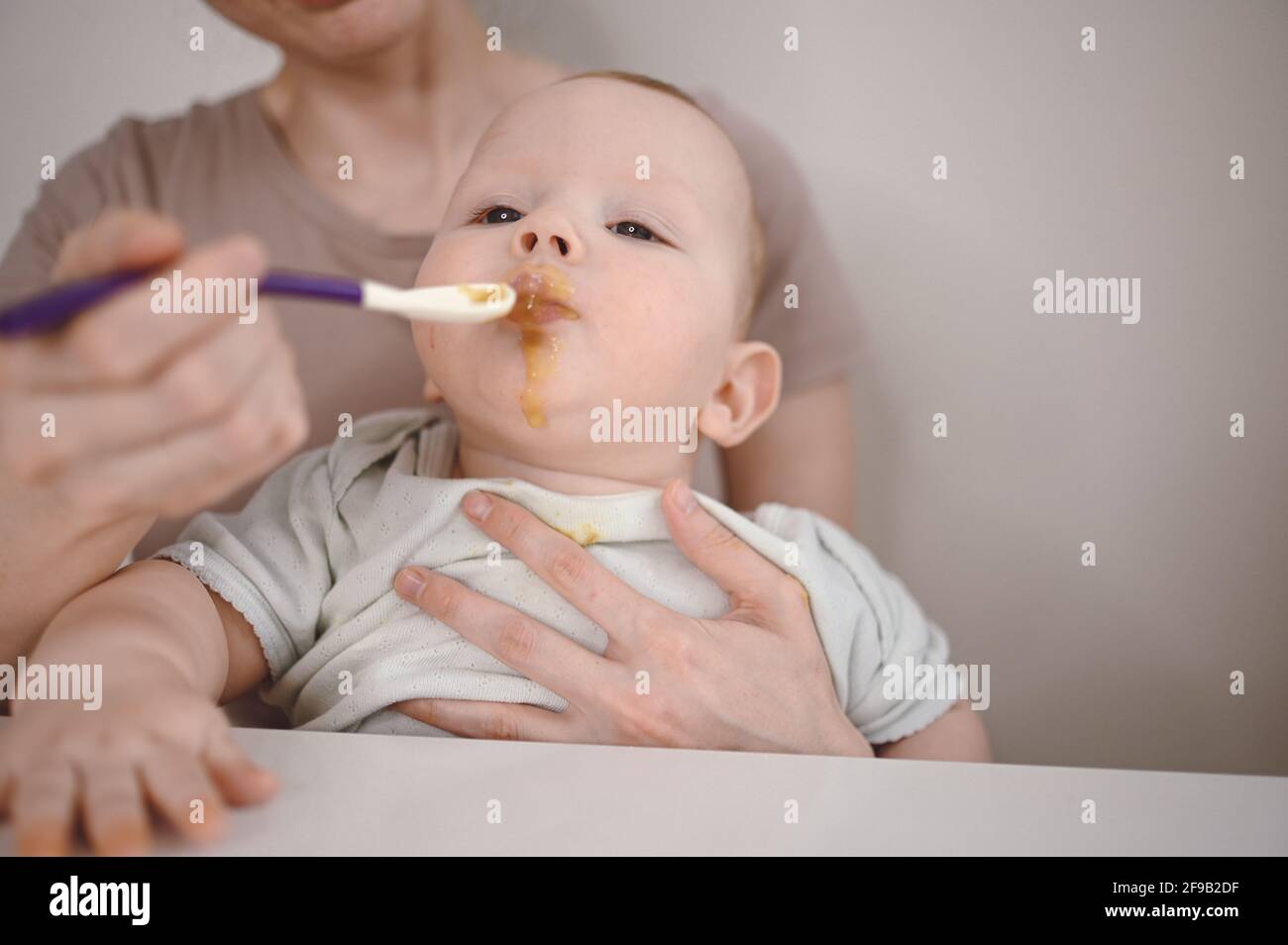 Petit Nouveau Ne Drole Bebe Garcon Apprendre A Manger De La Puree De Legumes Ou De Fruits Dans Un Pot En Verre Avec Une Cuillere Jeune Mere Aidant Petit Fils A Manger La