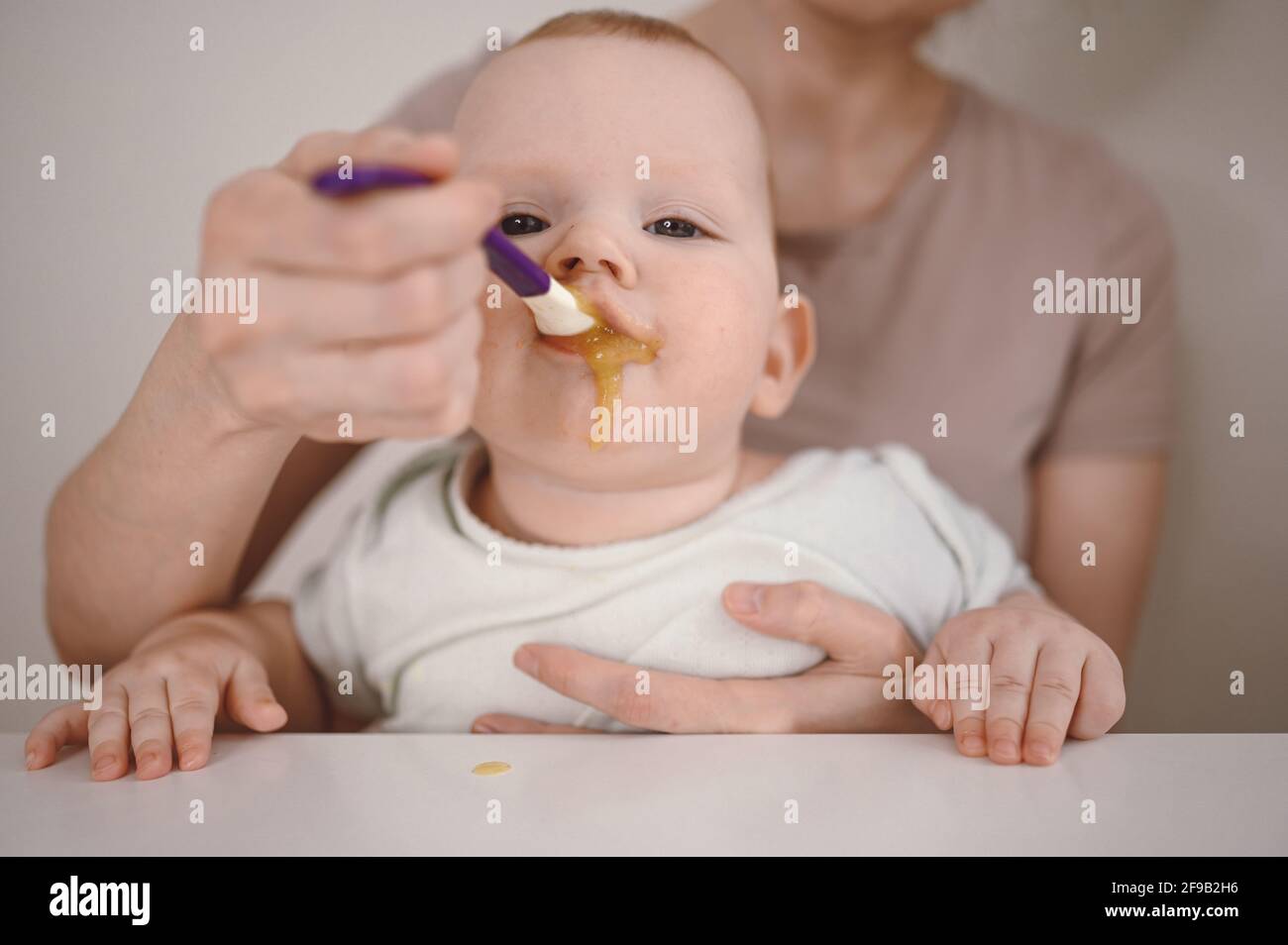 Petit nouveauné drôle bébé garçon apprendre à manger de la purée de légumes ou de fruits dans