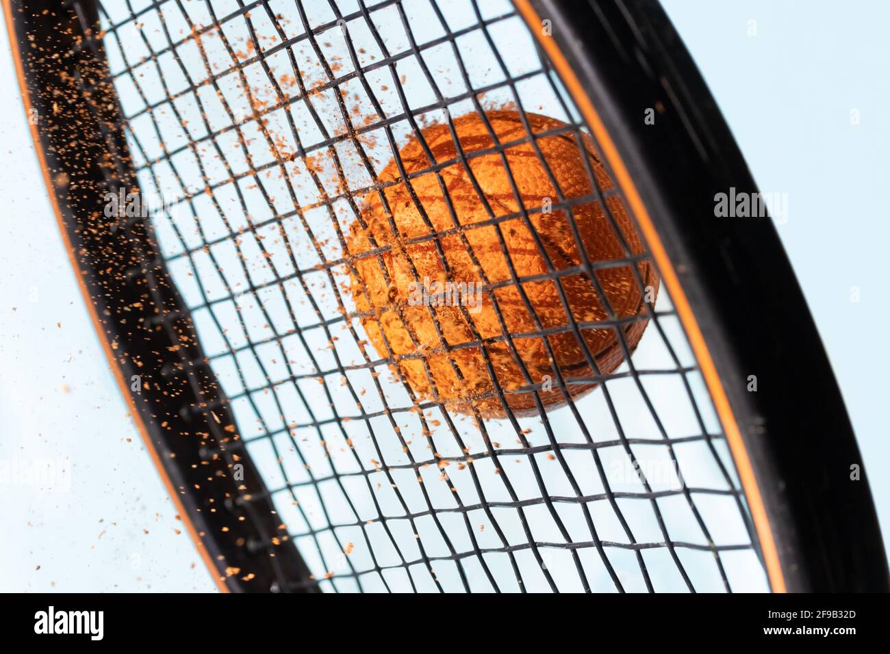 Un succès avec une raquette de tennis à une balle sale avec l'argile rouge volante autour, un fond de ciel bleu, vue rapprochée Banque D'Images