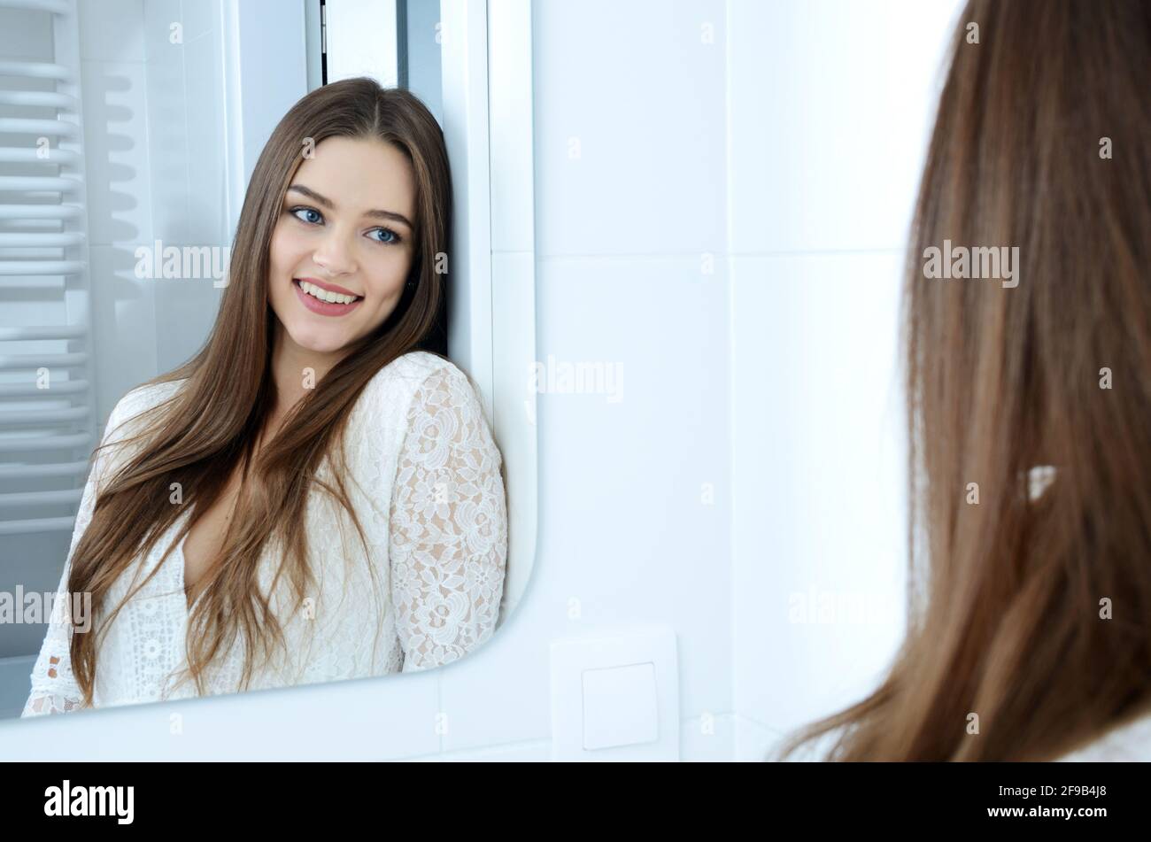 Jeune femme dans la salle de bains. Modèle polonais souriant dans la réflexion du miroir. Banque D'Images