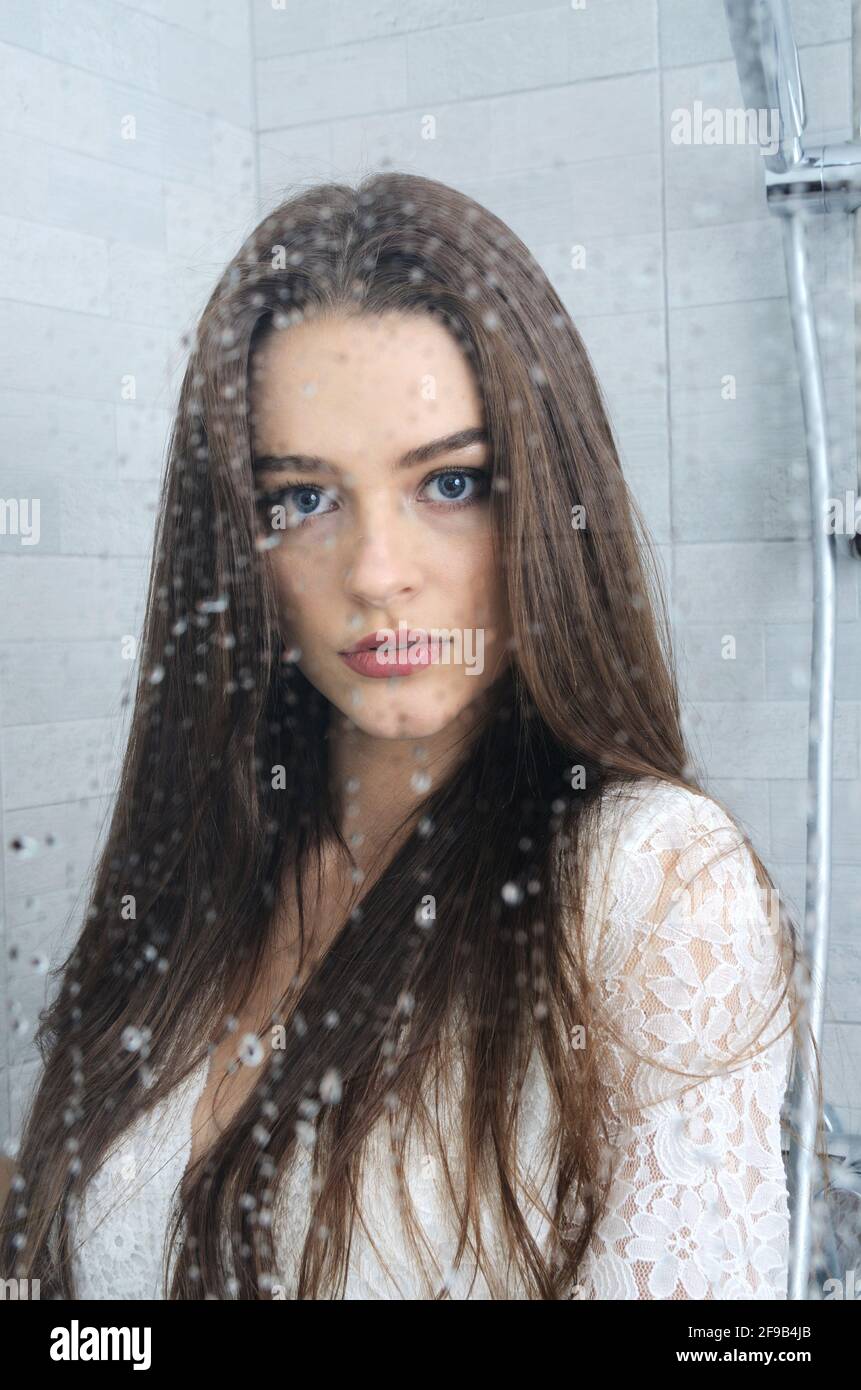 Jeune femme dans la salle de bains. Portrait de femme avec verre humide, gouttes d'eau devant son visage. Banque D'Images