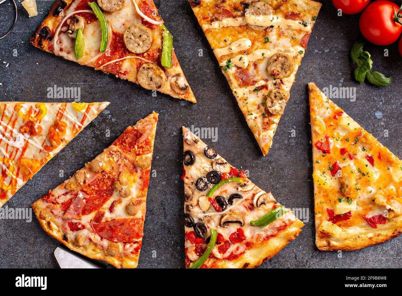 Variété de tranches de pizza vue de dessus sur fond sombre Banque D'Images