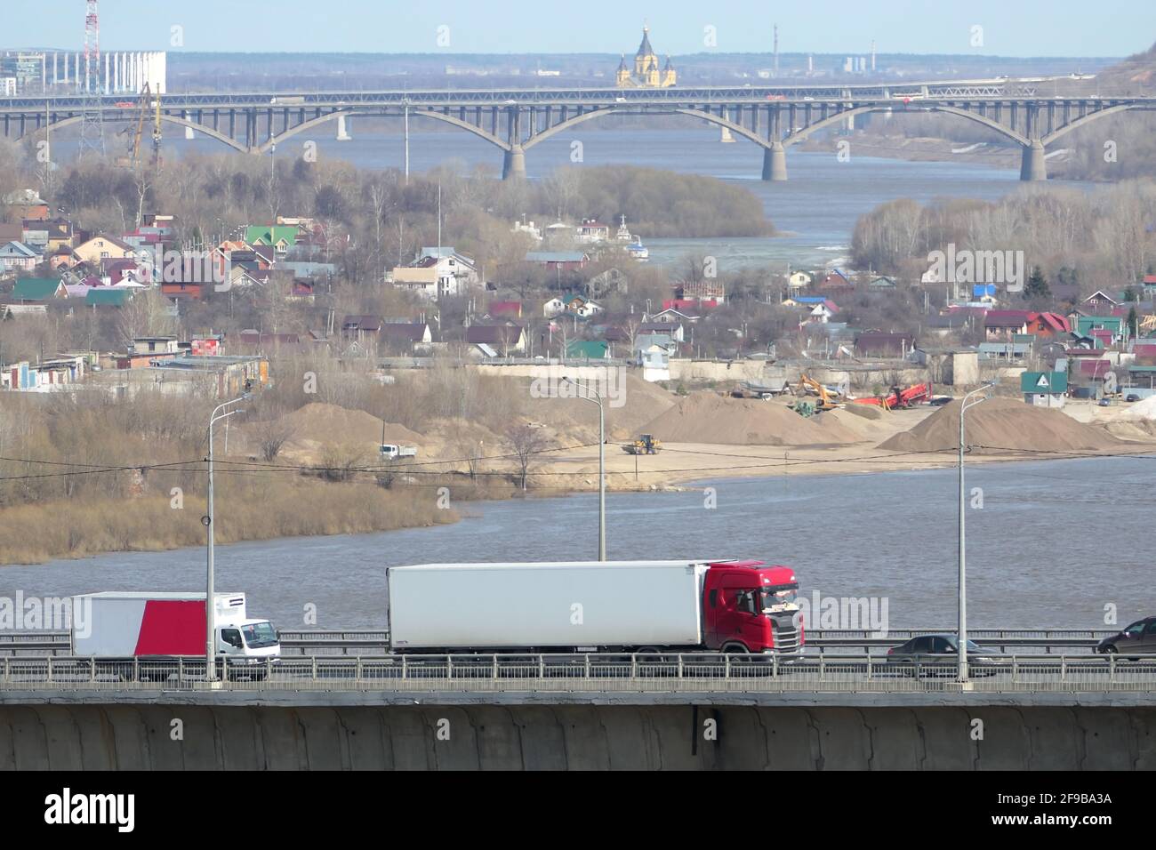 De grands camions franchissant le pont au-dessus de la rivière dans la ville. Banque D'Images