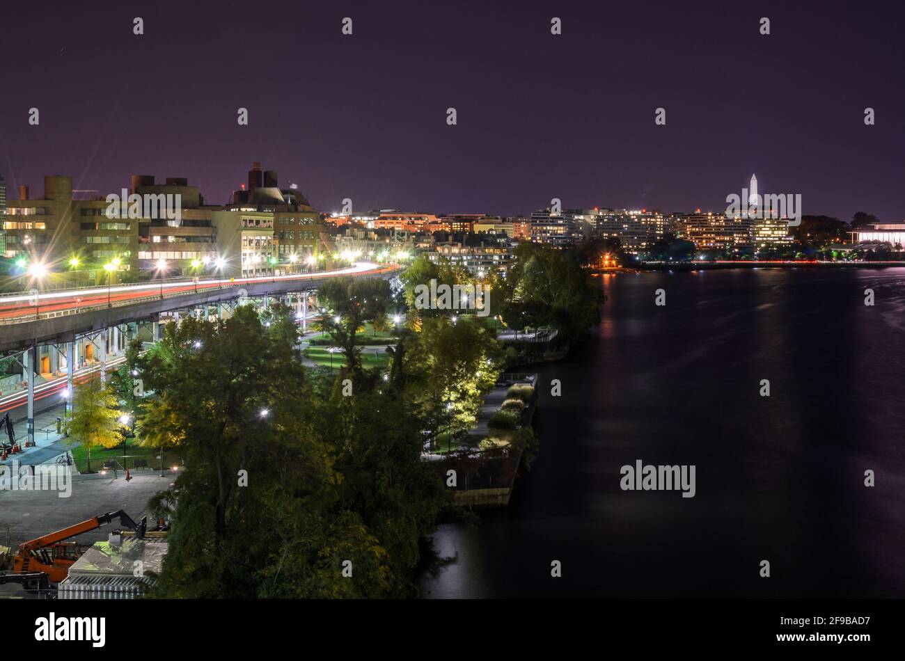 Vue sur la ligne d'horizon de Washington DC avec une autoroute surélevée longeant la rive du fleuve Potomac la nuit. Sentiers de lumière. Banque D'Images