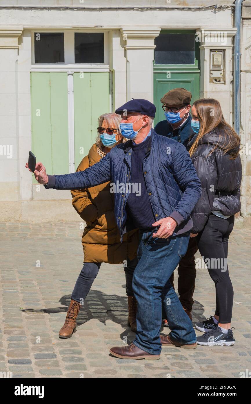 Groupe de personnes dans la rue avec homme prenant des photos au téléphone - Loches, Indre-et-Loire, France. Banque D'Images