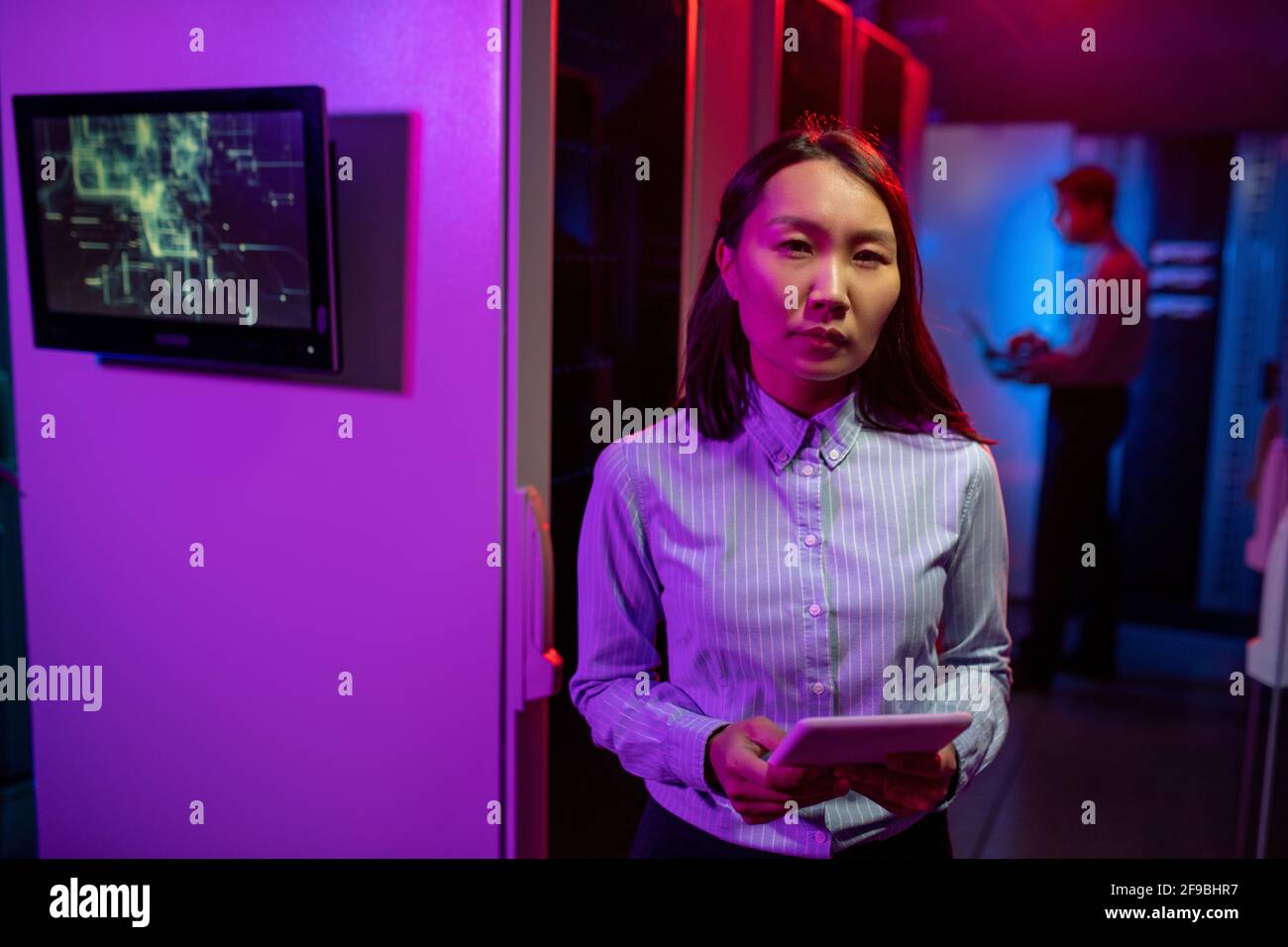 Portrait d'une femme asiatique sérieuse administrateur réseau debout avec une tablette contre les armoires informatiques dans la salle des serveurs Banque D'Images