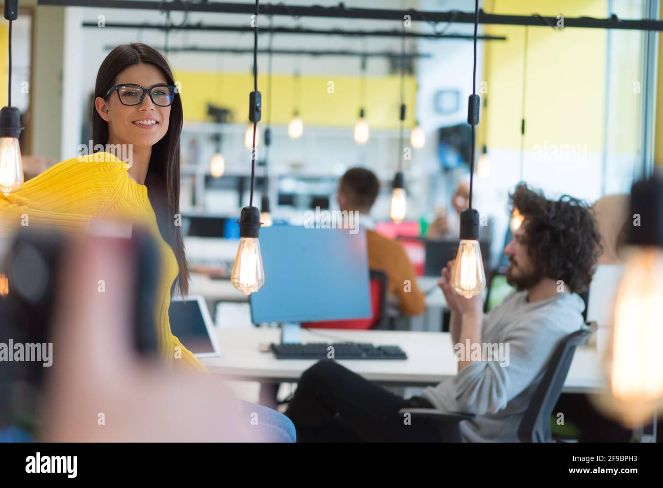 Portrait d'une jeune femme d'affaires décontractée et heureuse debout avec un ordinateur portable sur son lieu de travail dans un espace de travail moderne. Banque D'Images