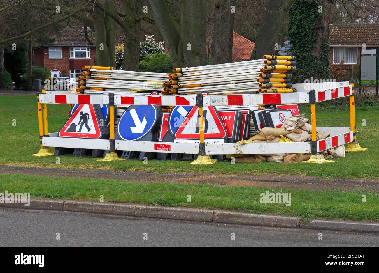 Barrières et signalisation déposées et stockées sur un green dans une zone résidentielle prête pour les travaux routiers à Hellesdon, Norfolk, Angleterre, Royaume-Uni. Banque D'Images