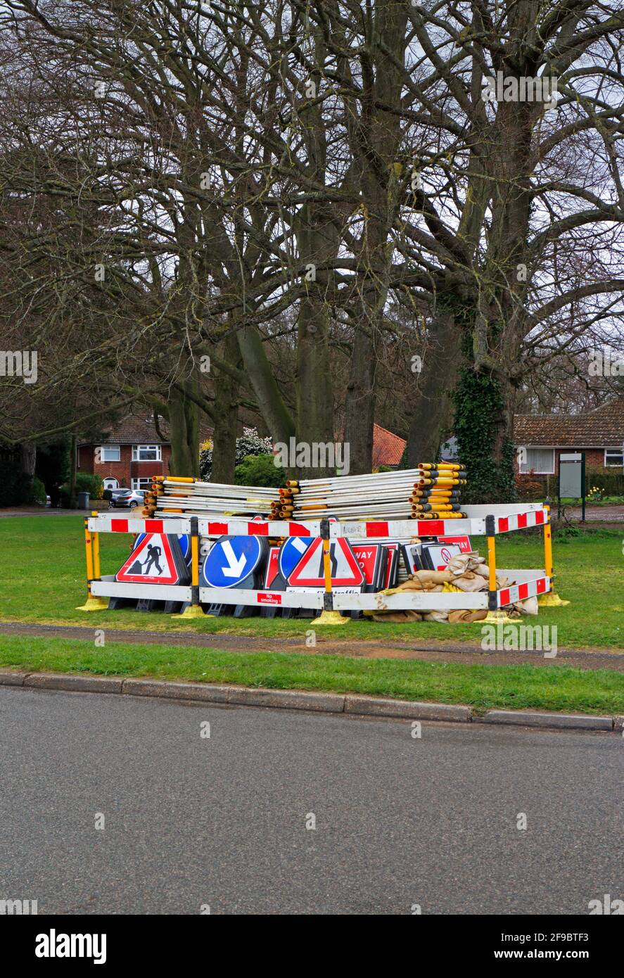 Barrières et signalisation déposées et stockées sur un green dans une zone résidentielle prête pour les travaux routiers à Hellesdon, Norfolk, Angleterre, Royaume-Uni. Banque D'Images
