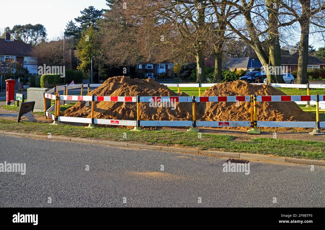 Gâcher les tas de terre entreposées par les excavations de services publics dans un quartier résidentiel de Hellesdon, Norfolk, Angleterre, Royaume-Uni. Banque D'Images