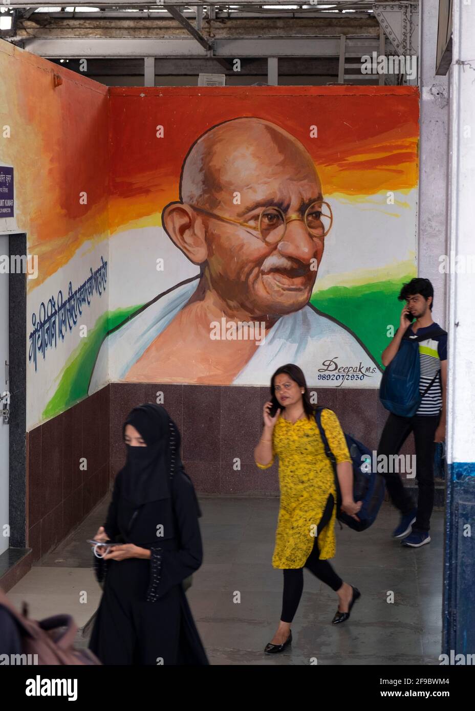 Commuter marchant au-delà d'une image de Mahatma Gandhi à l'intérieur de la gare de Dadar à Mumbai, Maharashtra, Inde, Asie. Banque D'Images