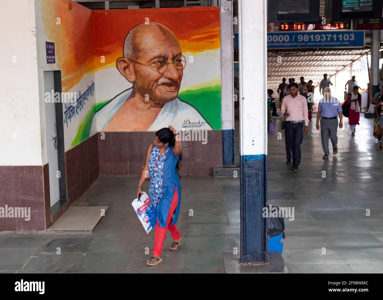 Commuter marchant au-delà d'une image de Mahatma Gandhi à l'intérieur de la gare de Dadar à Mumbai, Maharashtra, Inde, Asie. Banque D'Images