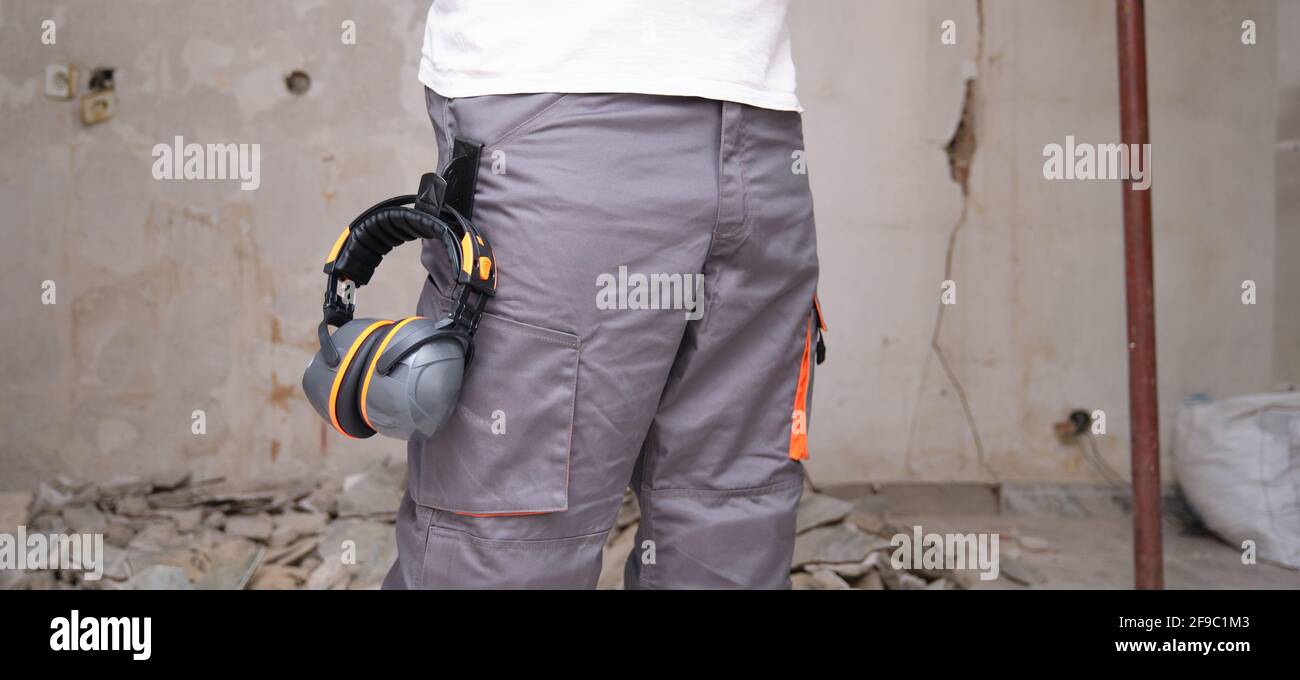 Un fabricant méconnaissable avec une protection auditive accrochée au pantalon. Concept de sécurité au travail. Banque D'Images