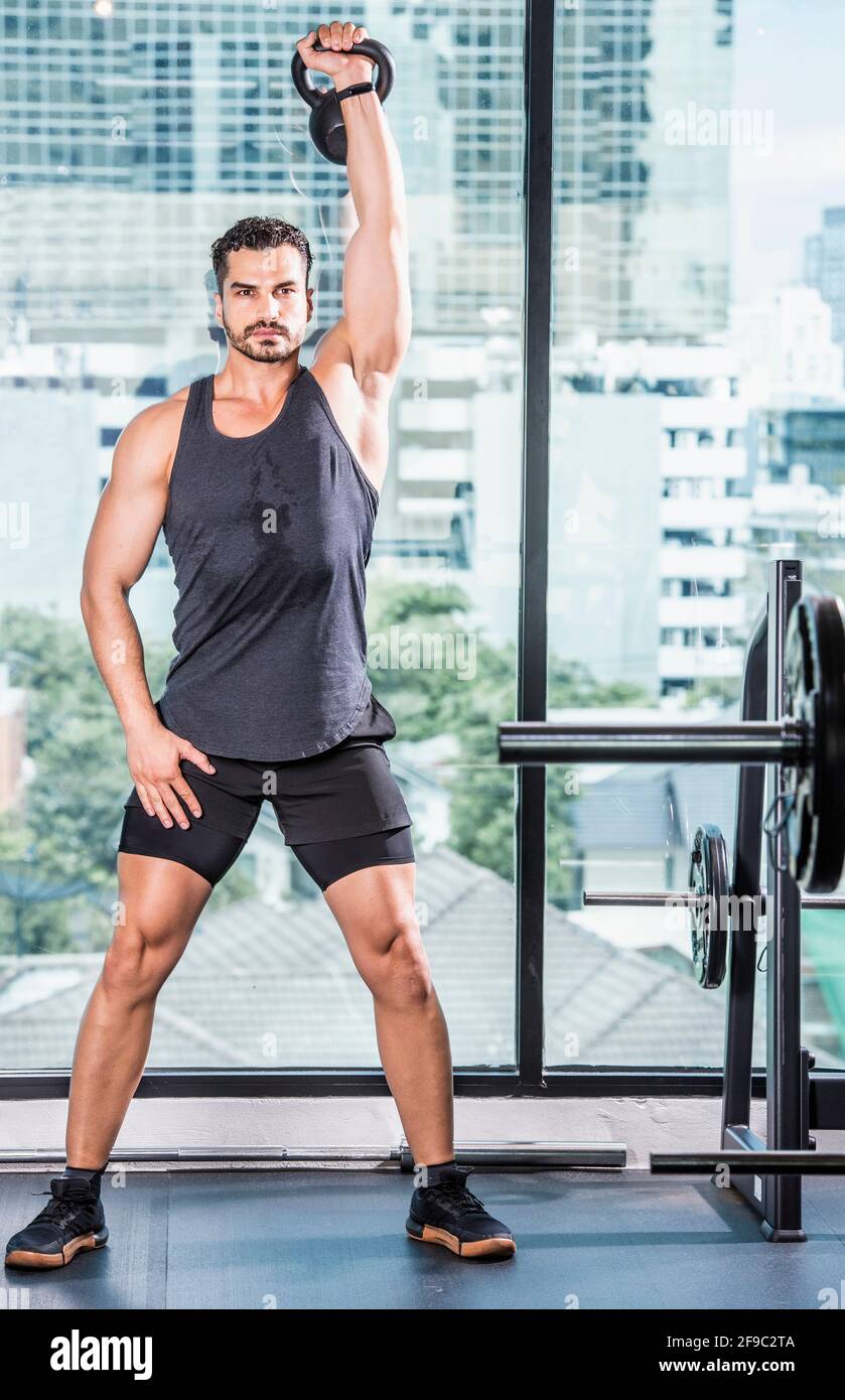 Les hommes s'exercent avec la cloche de la bouilloire à la salle de gym à Bangkok Banque D'Images
