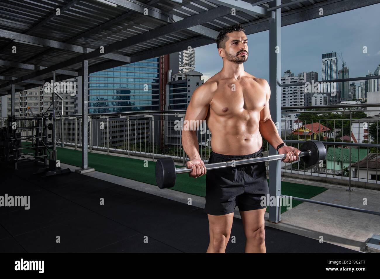 Hommes exerçant des boucles biceps à la salle de sport sur le toit à Bangkok Banque D'Images