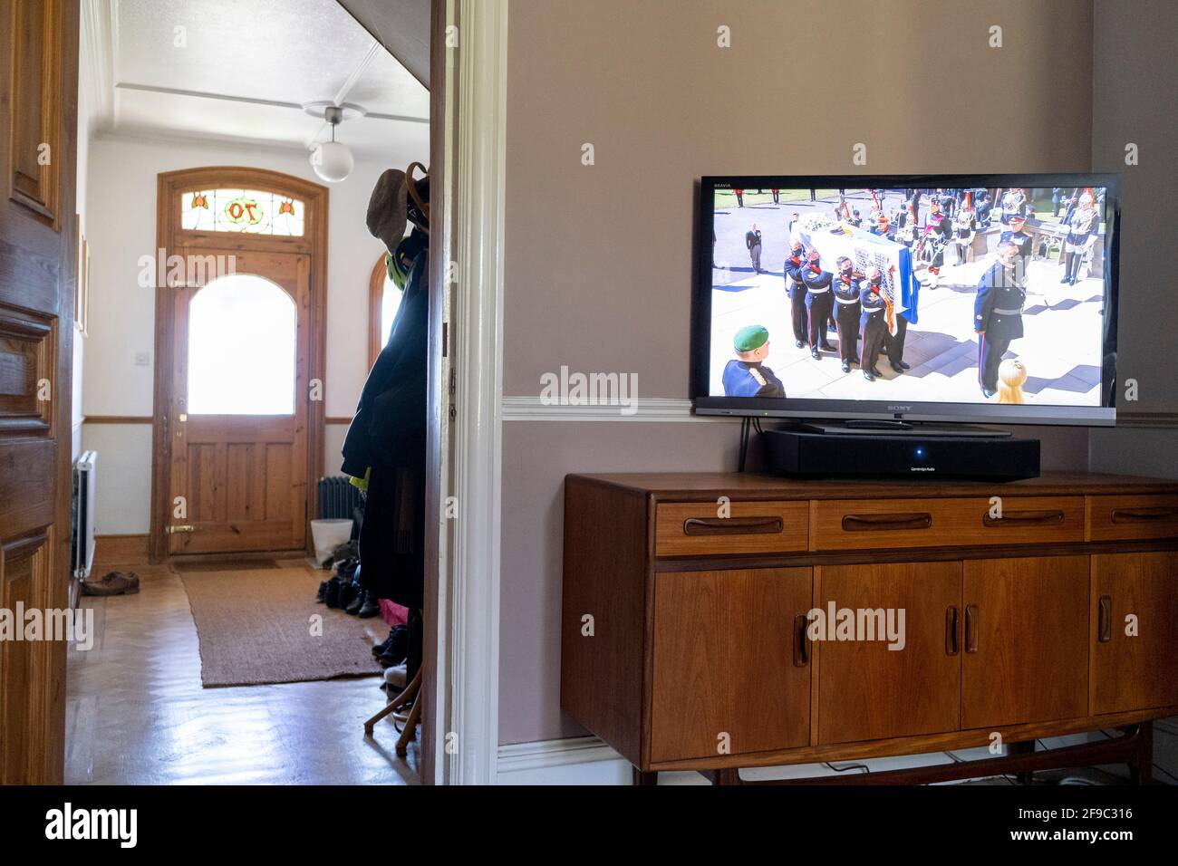 Les funérailles du prince Philip, duc d'Édimbourg et mari de la reine Elizabeth II, sont diffusées à la télévision britannique du château de Windsor et regardées dans le salon par une famille du sud de Londres, le 17 avril 20231, à Londres, en Angleterre. En raison des restrictions continues en cas de pandémie du coronavirus, le public a été invité à éviter de se joindre à la foule lors de grands rassemblements et à regarder la cérémonie à la maison. Banque D'Images