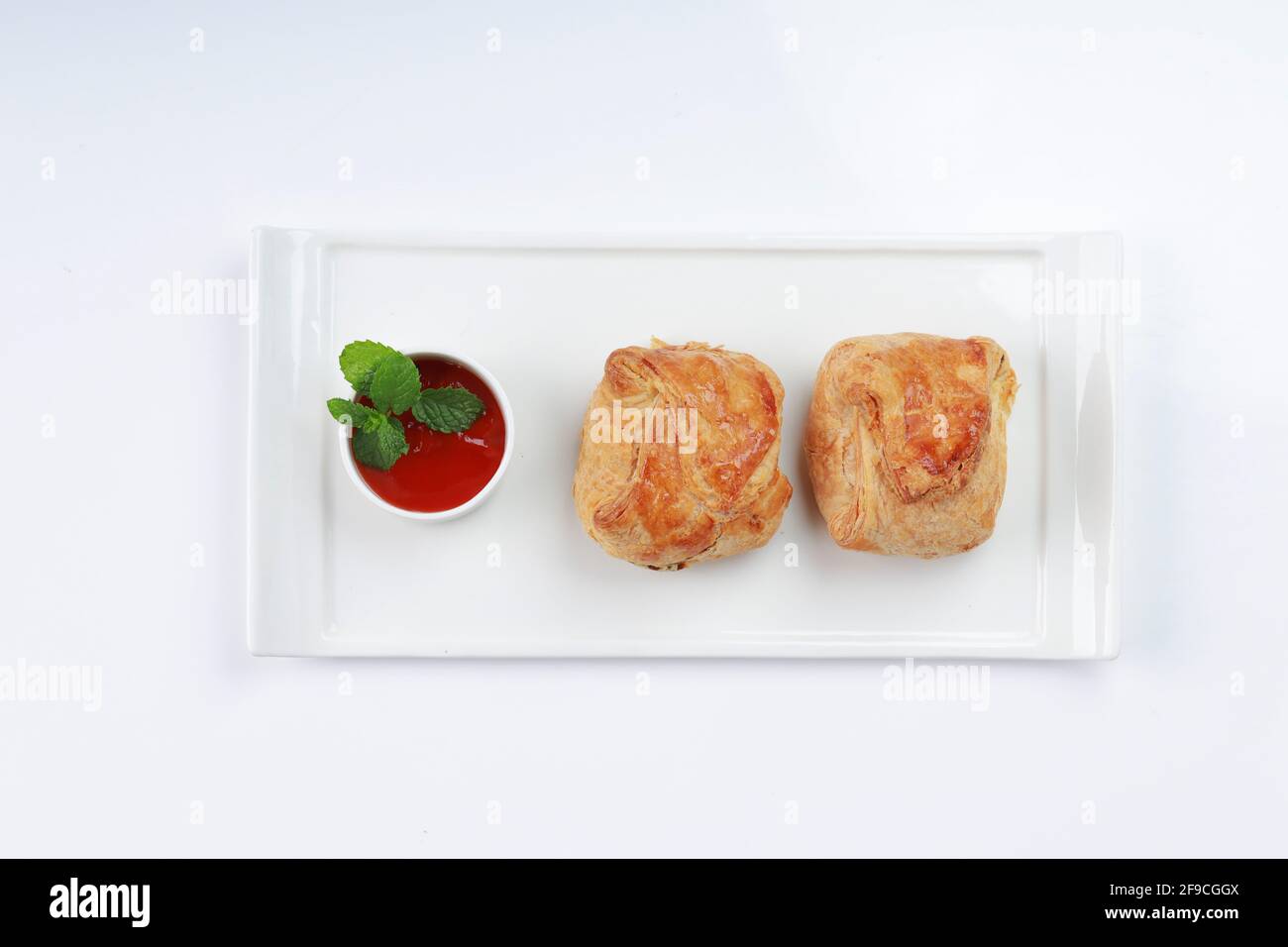 Pâte feuilletée aux œufs remplie de masala épicé et savoureux et placée sur une vaisselle blanche avec sauce tomate comme accompagnement sur fond blanc texturé, i Banque D'Images