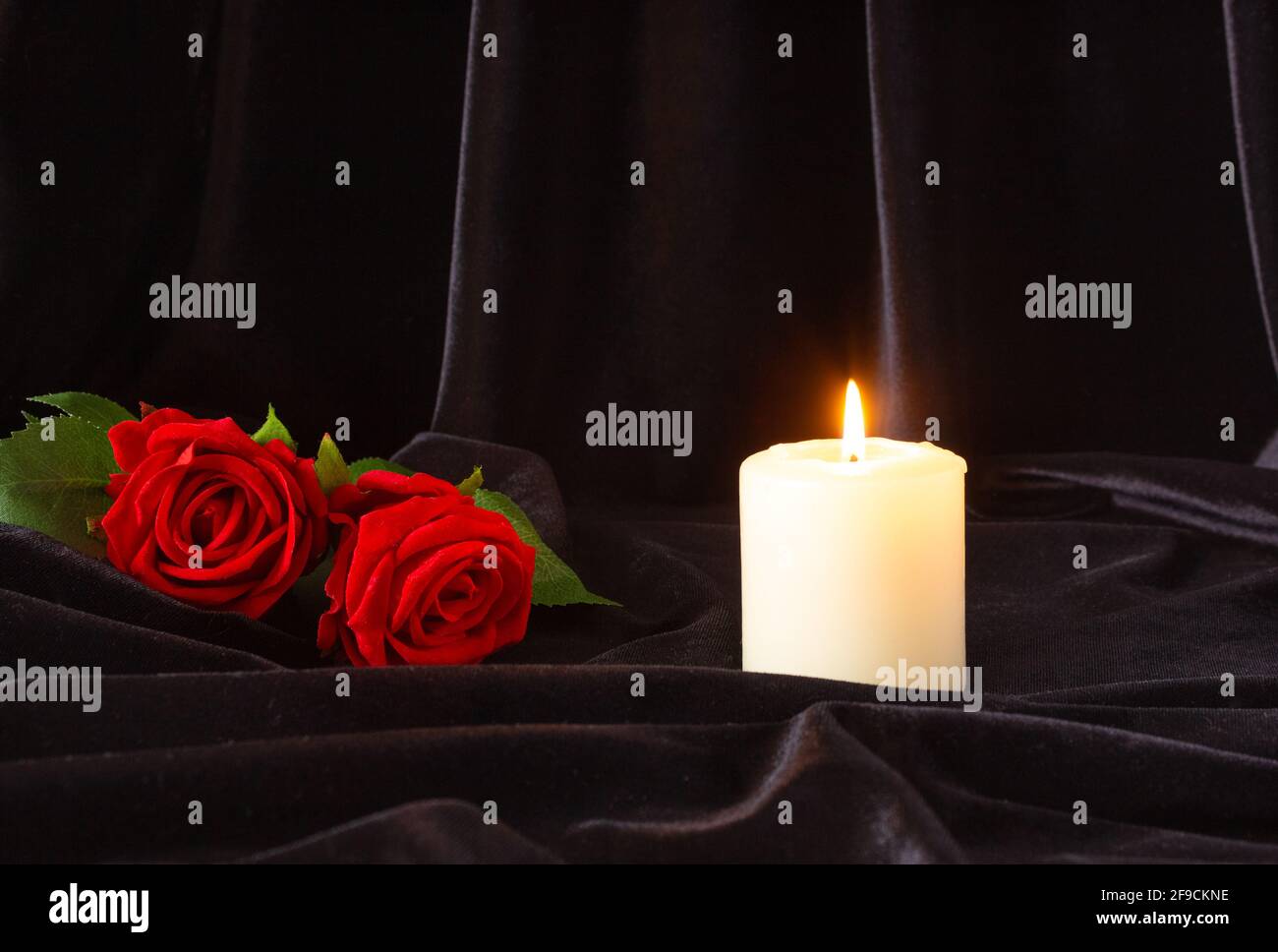 Une bougie allumée et une rose rouge sur fond noir. Le concept de condoléances, de deuil et de funérailles. Banque D'Images