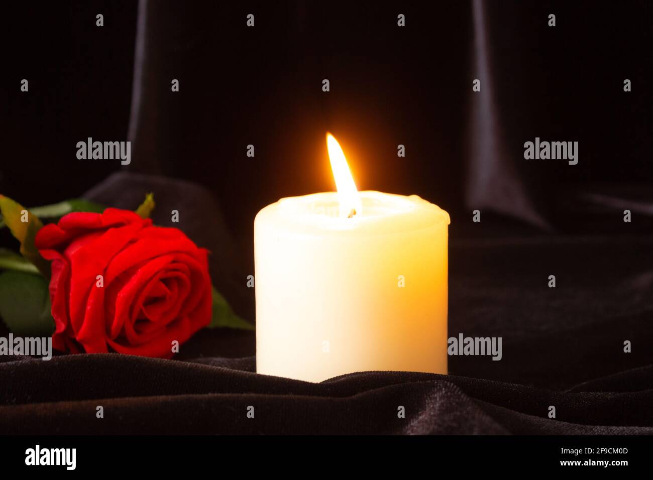 Une bougie allumée et une rose rouge sur fond noir. Le concept de  condoléances, de deuil et de funérailles Photo Stock - Alamy