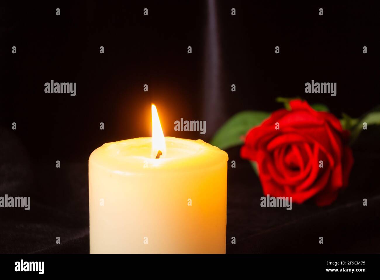 Une bougie allumée et une rose rouge sur fond noir. Le concept de  condoléances, de deuil et de funérailles Photo Stock - Alamy