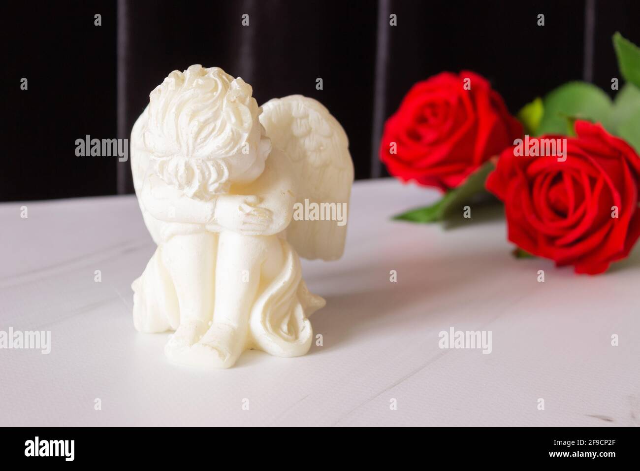 Une Petite Sculpture D Un Ange De Bebe Avec Des Ailes Et Une Rose Rouge Sur Fond Noir Le Concept Des Funerailles Des Condoleances Et Du Deuil Photo Stock Alamy