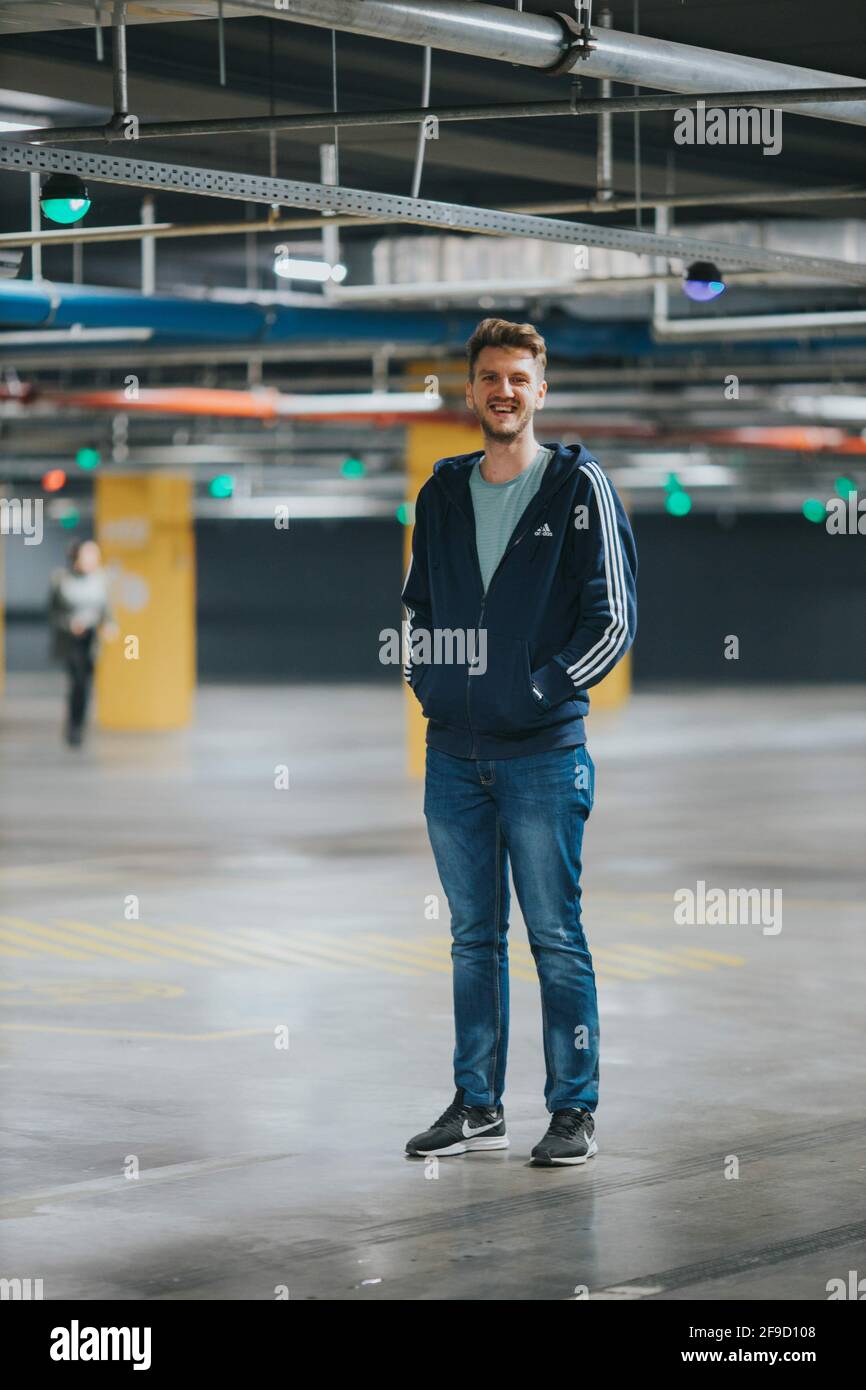 BRCKO, BOSNIE-HERZÉGOVINE - 27 novembre 2019 : jeune homme debout dans un garage portant un sweat-shirt Adidas Banque D'Images
