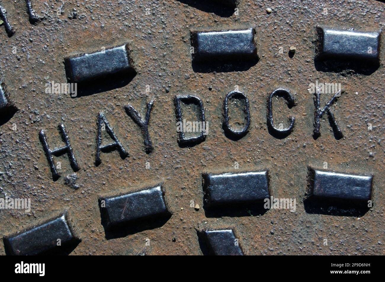 Un trou d'homme en fonte couvrant un drain marqué de la ville de Haydock, à Merseyside, vue par une journée ensoleillée. Banque D'Images