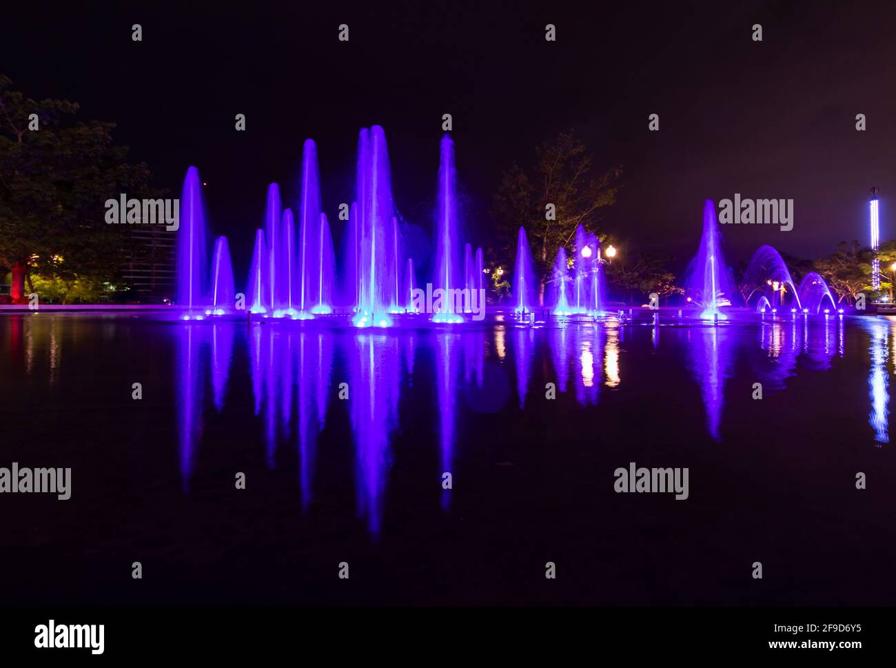 Photo en accéléré d'une fontaine colorée la nuit - nuances de violet et de bleu Banque D'Images