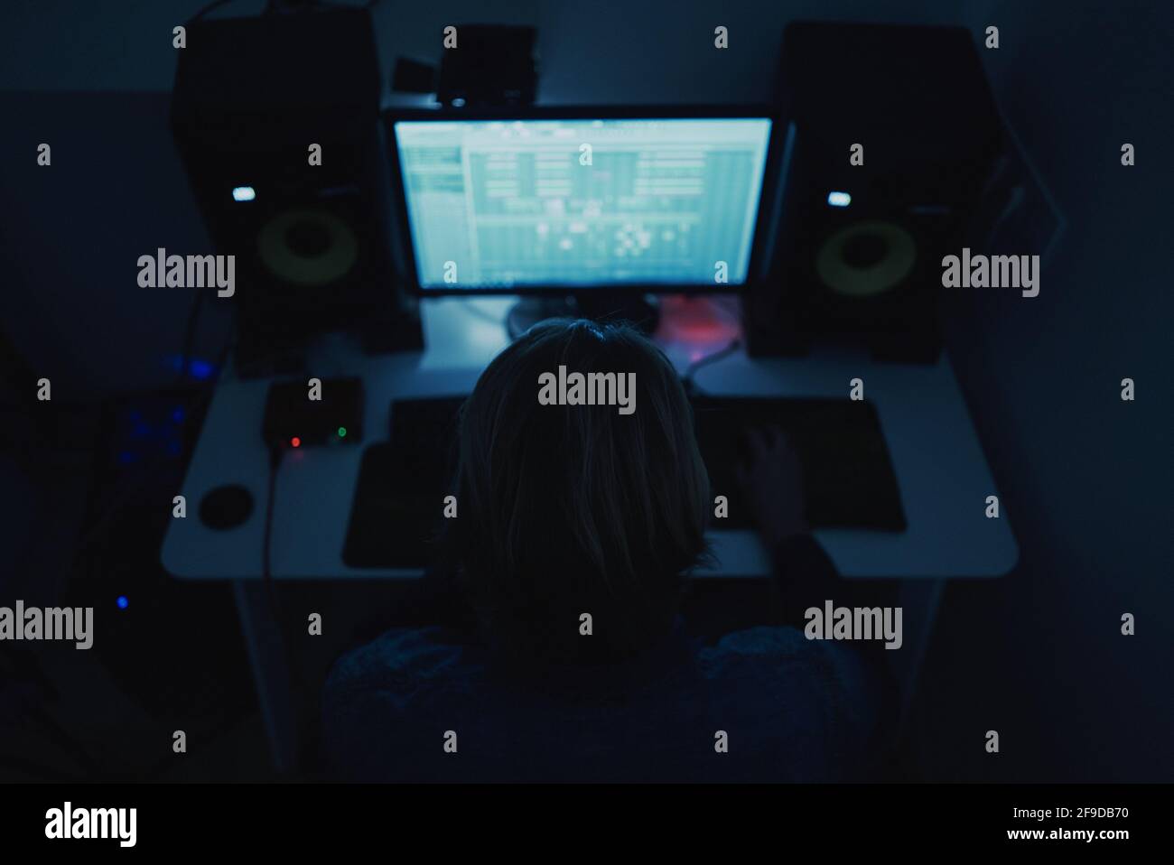 Petit foyer d'un producteur adulte composant de la musique avec un ordinateur dans une pièce sombre Banque D'Images
