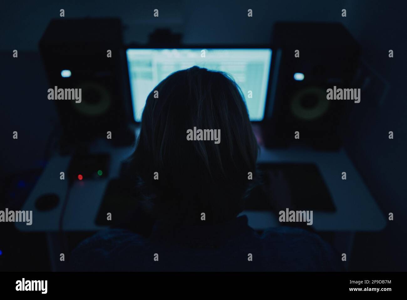 Petit foyer d'un producteur adulte composant de la musique avec un ordinateur dans une pièce sombre Banque D'Images