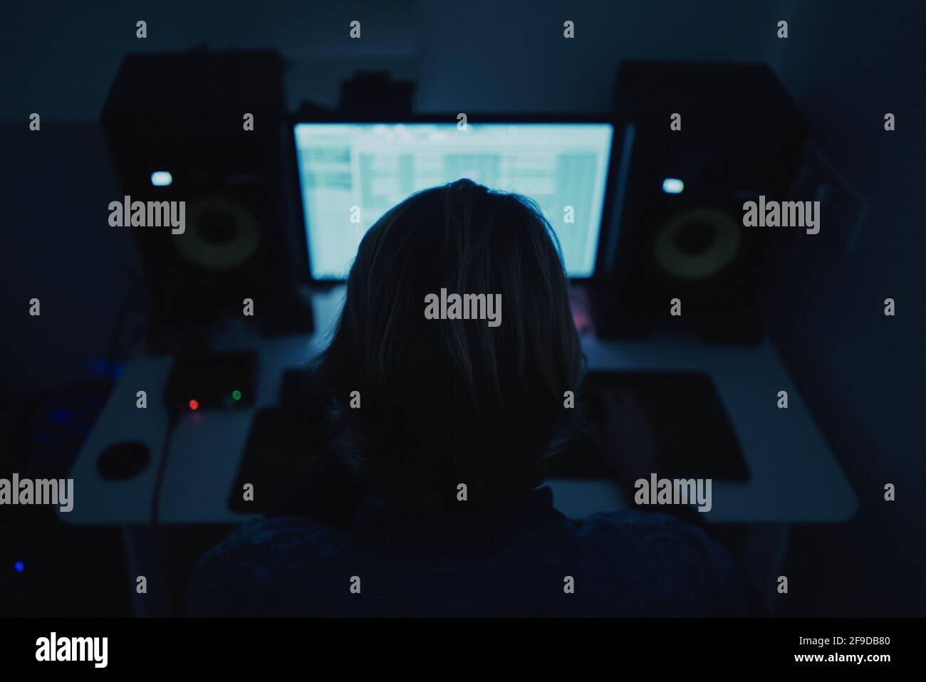 Petit foyer d'un producteur adulte composant de la musique avec un ordinateur dans une pièce sombre Banque D'Images