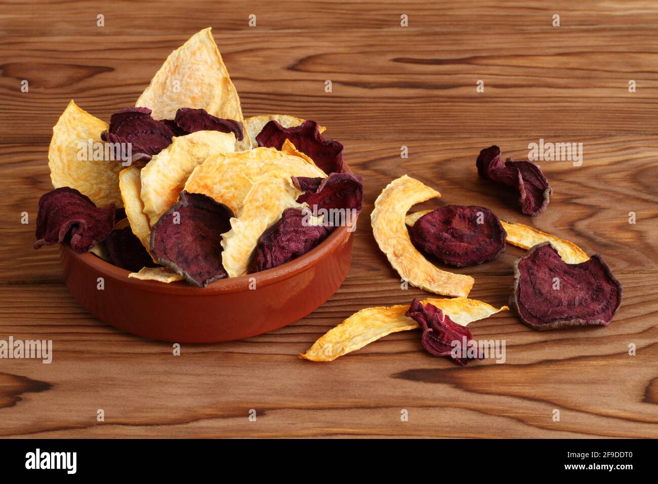 Mélange de betteraves séchées et de chips de légumes de citrouille dans un bol en céramique sur une table en bois. Gros plan. Macro Banque D'Images