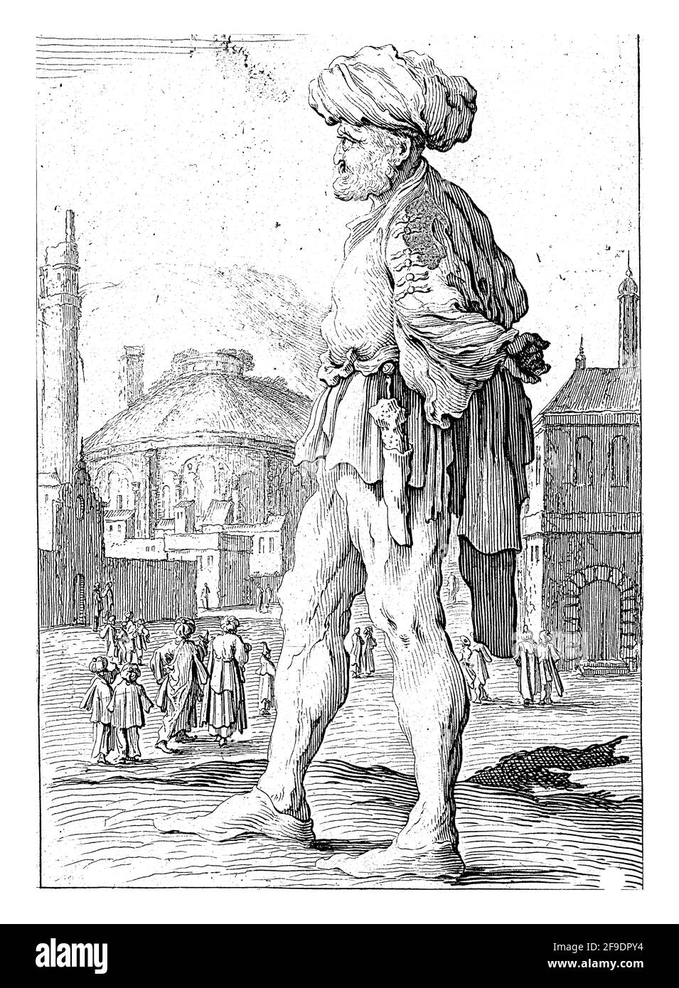 En face d'une ville se dresse un homme en vêtements orientaux avec un turban sur sa tête. Il a les mains derrière son dos. Un poignard sur la hanche. Banque D'Images