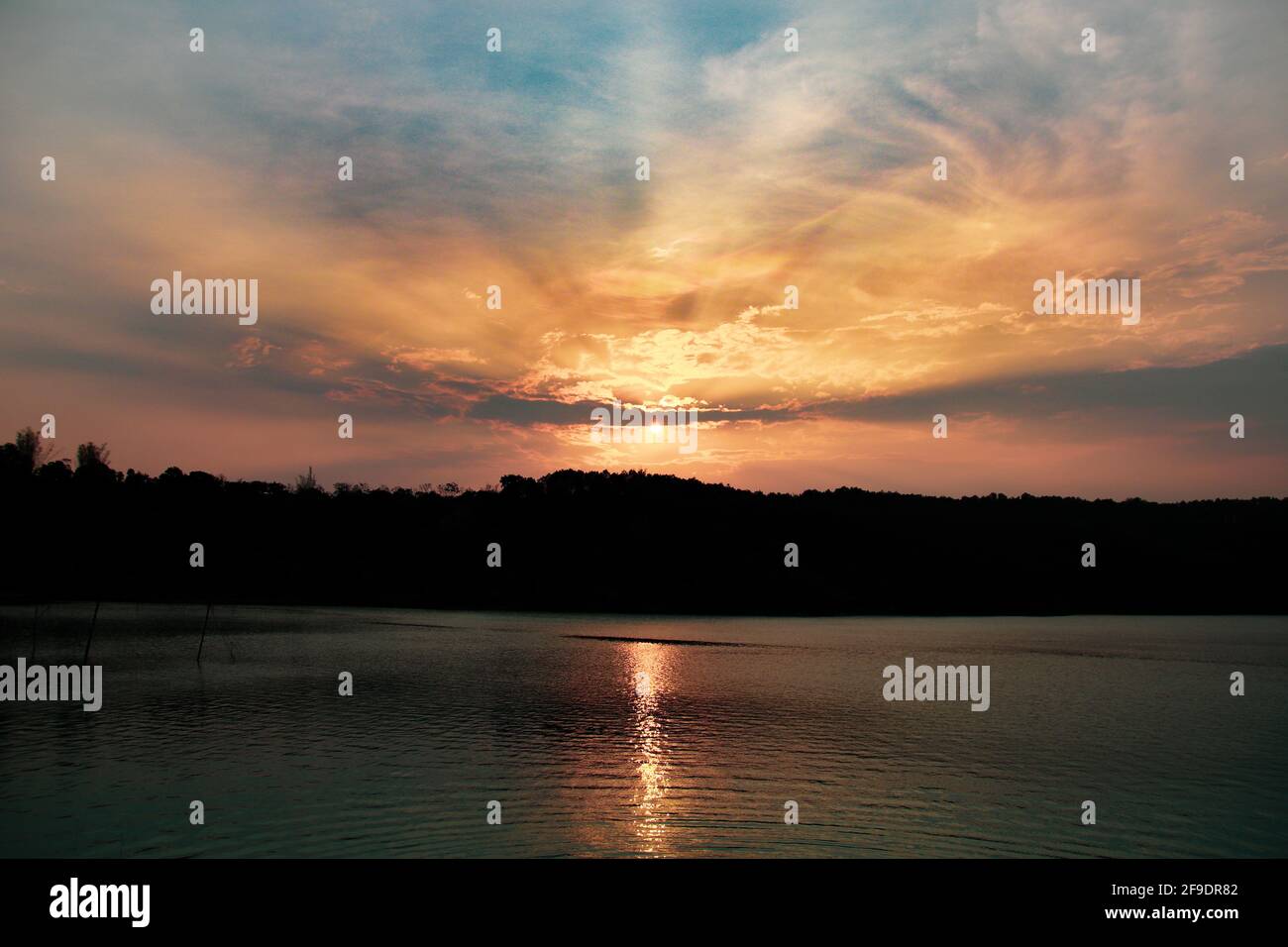 Un lac calme au coucher du soleil avec les rayons du soleil se reflétant dans l'eau Banque D'Images