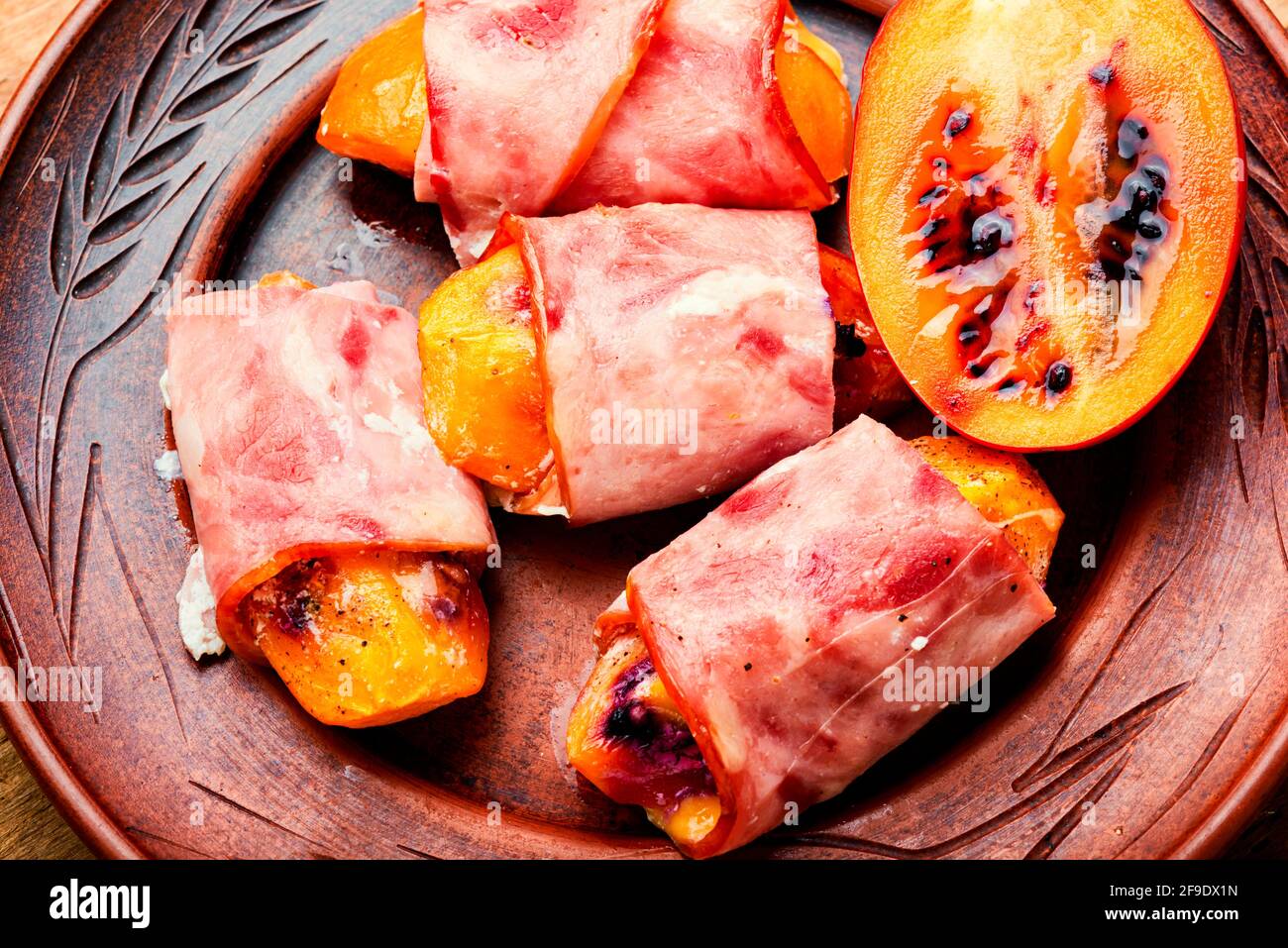 Morceaux de Tamarillo emballés et cuits avec du jambon et du bacon Banque D'Images