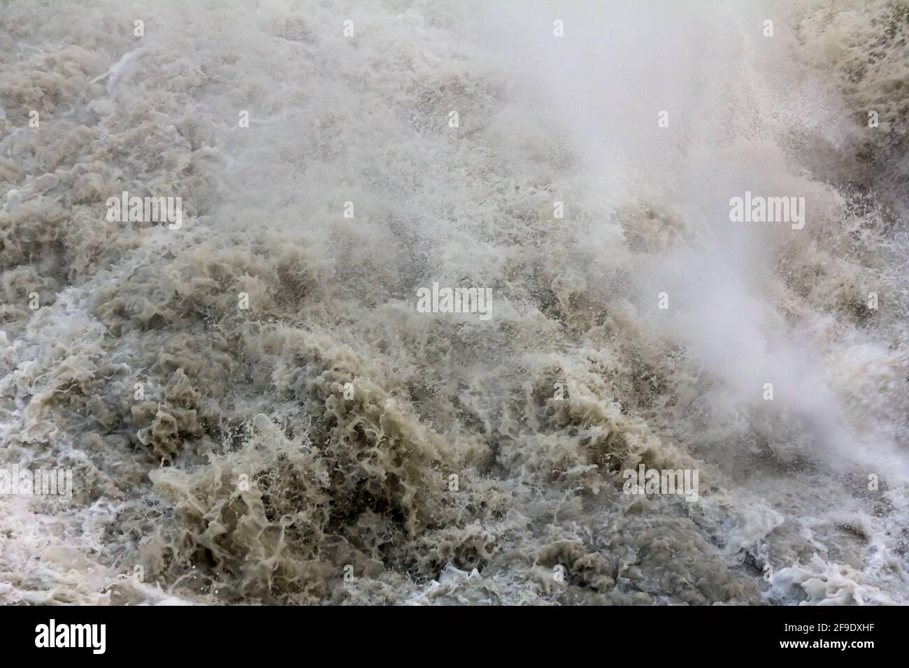 L'eau qui fait rage dans une rivière de montagne boueuse après une chute d'eau Banque D'Images