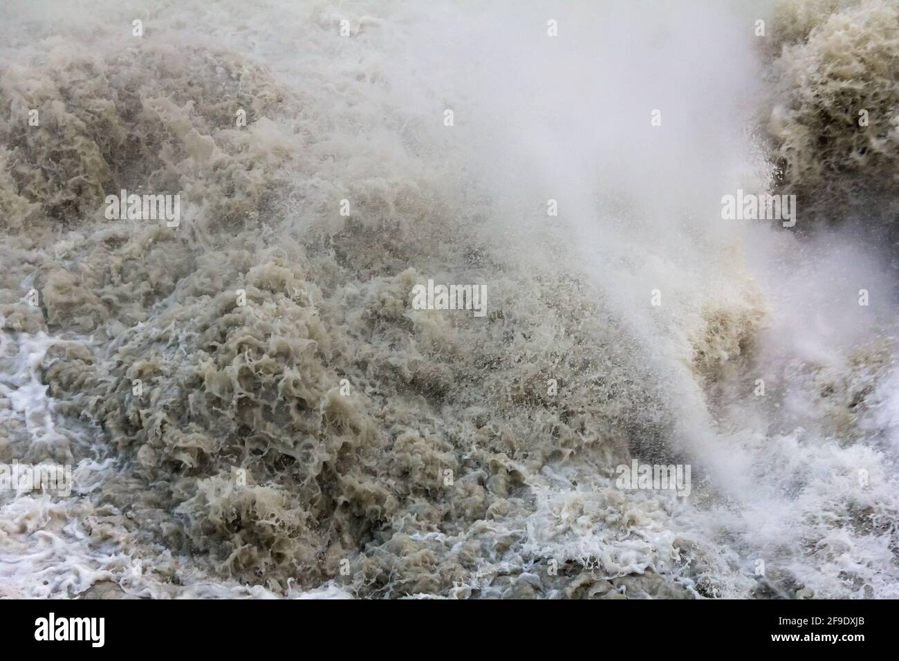 L'eau qui fait rage dans une rivière de montagne boueuse après une chute d'eau Banque D'Images