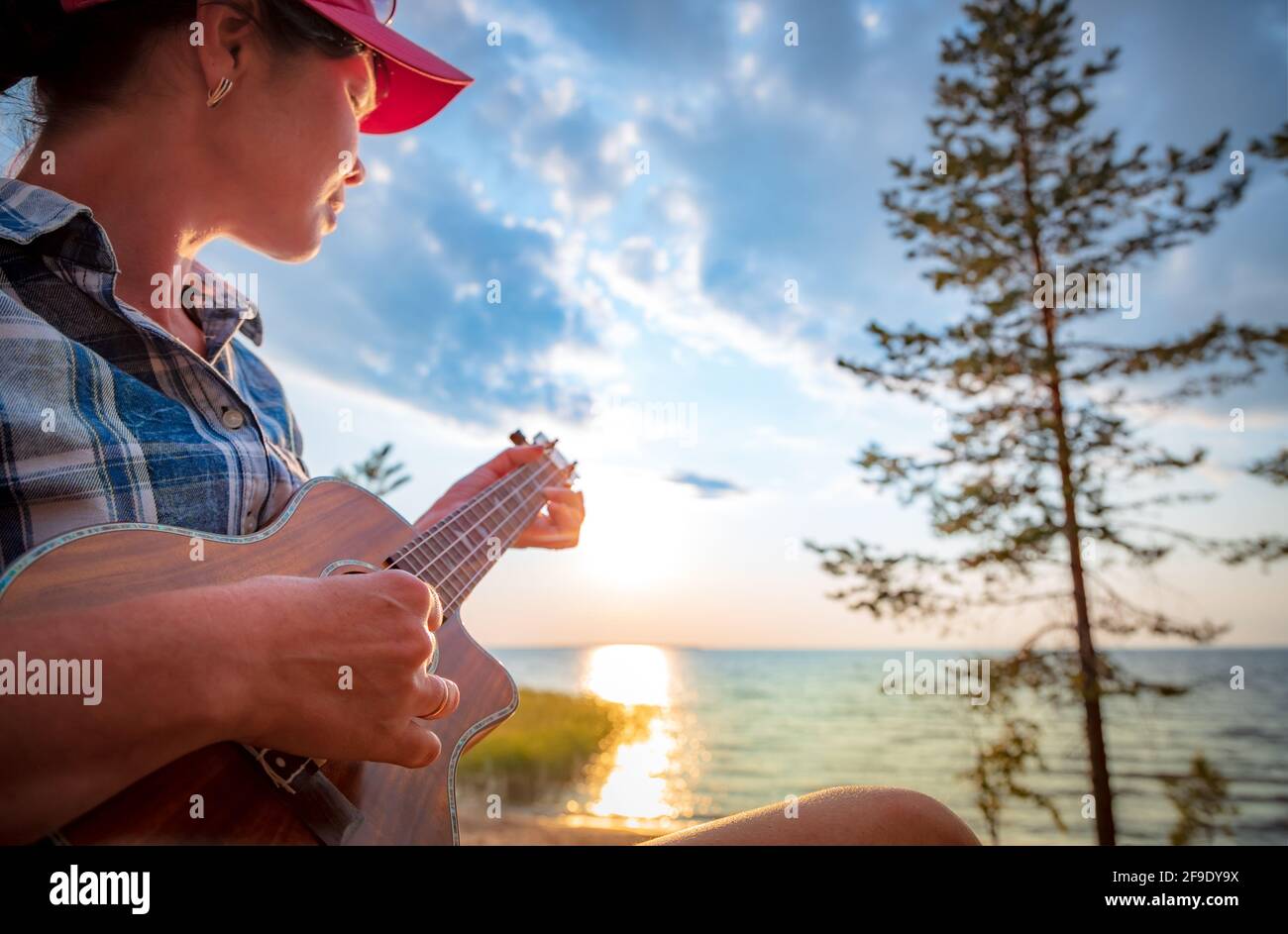 Femme au coucher du soleil à jouer du ukulele Banque D'Images